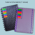 Caderno de disco universitário com capa dura, apresentando páginas em preto e roxo, e marcadores coloridos.