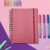 Caderno Smart Médio com folhas reposicionáveis, rodeado por canetas coloridas e clipes de papel.