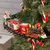 Trem natalino decorativo suspenso em uma árvore de Natal, com luzes e movimento, apresentando vagões com presentes e um Papai Noel.