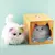 Huggy Pets: bichinho de pelúcia interativo com orelhas coloridas, olhos que piscam e embalagem ao fundo.