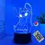 Luminária 3D LED com a personagem Stitch da Disney, iluminada em azul.