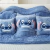 Conjunto de almofadas com estampas do personagem Stitch, da Disney, em um sofá coberto por um lençol azul.