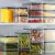 Porta Frios e Mantimentos de Acrílico transparente com tampa, ideal para armazenamento de alimentos.