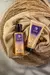 Produtos Levidè Cosméticos Naturais: Gel Esfoliante Cristais de Quartzo e Gel de Banho Multibenefícios em embalagens roxas e douradas sobre superfície de palha e tecido dourado