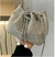 Cartera de mujer en gamuza con strass, tipo pouch, ideal para la noche o fiesta, sostenida con una mano.