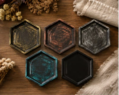 Bandejas hexagonales chicas de colores variados sobre mesa de madera con detalles de flores secas y telas