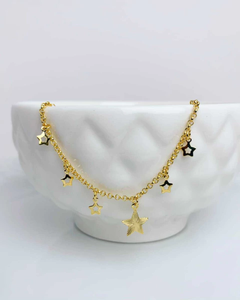 Pulseira dourada com pingentes de estrelas vazadas penduradas.