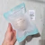Esponja facial blanca 100% Konjac en su empaque, sostenida con una mano, ideal para todo tipo de piel.
