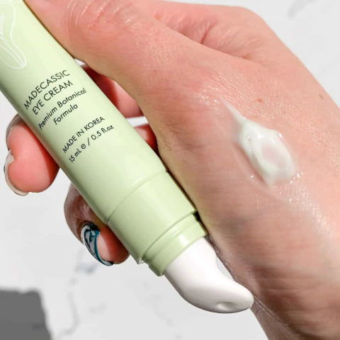 Crema para contorno de ojos Madecassic de Coony, mostrando el envase y una pequeña cantidad del producto en la mano.