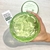 Gel hidratante de aloe vera y ácido hialurónico en un recipiente verde, visto desde arriba, con una mano sosteniéndolo.