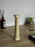 Columna dórica decorativa de color claro, con base cuadrada y detalles verticales, sobre una mesa de madera.