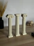 Tres columnas decorativas de estilo clásico en una mesa de madera, con detalles elaborados en sus capiteles.