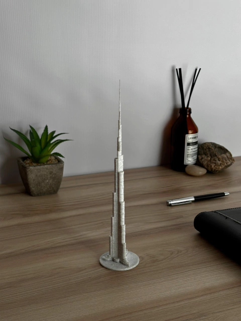 Maqueta del Burj Khalifa, el rascacielos más alto del mundo, sobre una mesa de madera con una planta y otros objetos decorativos.