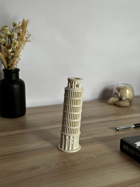 Maqueta de la Torre de Pisa, una famosa obra arquitectónica inclinada, sobre una mesa de madera.
