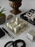 Maqueta del Congreso de la Nación Argentina, rodeada de objetos decorativos como plantas, un libro y accesorios de oficina.