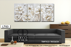 Tríptico LT03 con flores delicadas en tonos claros, decorando una pared sobre un sofá negro.