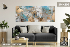 Un mural abstracto moderno en tonos azules, dorados y beige, decorando una pared sobre un sofá gris. El mural mide 128x52cm, complementando el ambiente del salón. DECODOMUM decora tu hogar!