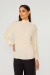 Modelo vestindo a Blusa Serena Creme com gola alta e mangas longas.