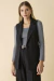Modelo vestindo colete de alfaiataria preto sobre blusa cinza.