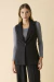 Colete de alfaiataria preto feminino, com fechamento de um botão, usado sobre blusa cinza de manga longa. Moda essencial e elegante.