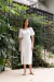 Modelo vestindo o Vestido Lille Branco em um jardim com folhagens ao fundo.