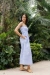 Modelo vestindo o Vestido Tricoline Mila Azul em um jardim tropical.