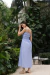 Modelo vestindo o Vestido Tricoline Mila Azul, com alças finas e comprimento midi, em um jardim ao ar livre.