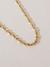 Colar torcido banhado a ouro 18k, com detalhes brilhantes sobre fundo claro.