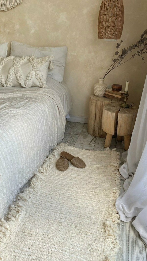 Alfombra Telar de 90cm x 50cm en un dormitorio, junto a una cama con almohadas blancas y pantuflas en el suelo.