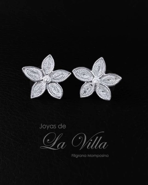 Aretes tipo topo en forma de flor con diseño de filigrana, elaborados en plata ley 950, con un punto de plata en el centro.