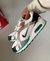 Zapatos Nike Air Max Correlate en color blanco, con detalles en gris y verde, sostenidos por una mano.