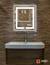 Espejo led rectangular ARD Glanz Luminous Glass de 60 x 52 cm en un baño moderno con lavabo y pared de piedra.