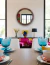 Round wooden mirror in a modern dining setting with colorful decor and tableware.
