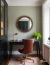Stylish wooden round mirror in a modern office space with a black desk and a brown chair.