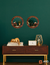 Set de 2 espejos redondos ARD Glanz Oak de 43 cm sobre una pared verde, con una decoración elegante en una consola de madera oscura.