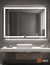 Espejo rectangular LED Glanz Luminous Glass Prestige en un baño moderno, con un lavabo blanco y decoración minimalista.