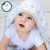 Bebê sorrindo com toalhão de banho estampado com capuz, feito 100% de algodão.