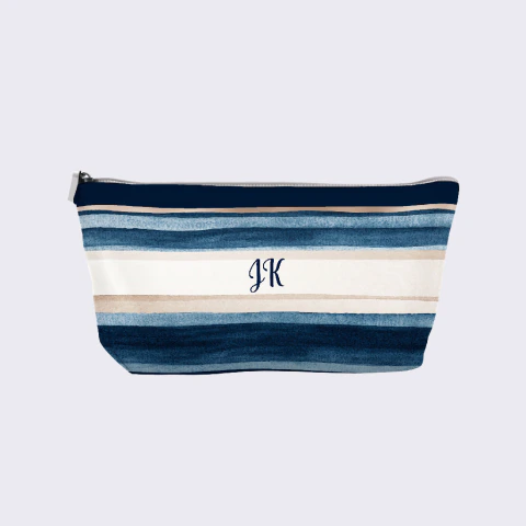 Necessaire personalizada com estampa de listras azuis e bege, confeccionada em tecido Oxford, com fechamento em zíper e iniciais "JK" no centro.