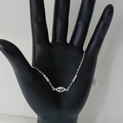 Pulseira de prata 925 com bolinhas e olho grego com zircônia azul, exibida em uma mão de manequim.