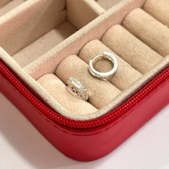 Brinco argolinha cravejado de zircônias em prata 925 dentro de uma caixa de joias vermelha.