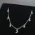Colar choker em prata 925 com pingentes de luas e estrelas, em fundo preto.