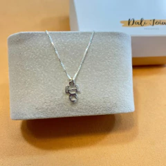 Corrente de prata 925 com pingente em forma de menina pequena exposta em um display.