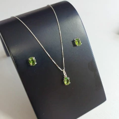 Conjunto de joias em prata 925 com zircônias na cor peridoto, incluindo um colar e brincos em exibição.