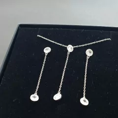 Conjunto de zircônias em prata 925, apresentando um colar com pingentes longos, sobre um fundo preto.