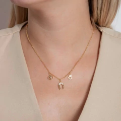 Colar dourado com pingentes de Olho Grego, Ferradura e Mão de Fátima cravejados de zircônias, usado por uma mulher.