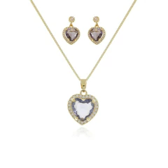 Conjunto de semijoias com colar e brincos em formato de coração cravejados, nas cores lilás e cristal.