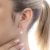 Brinco argolinha com pérola, em formato delicado, usado em uma orelha feminina.