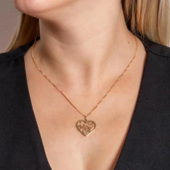 Colar semijoia dourado com pingente em formato de coração com a palavra "Mãe" usado por mulher