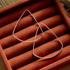 Brinco argola triângulo em prata 925, exibido sobre um fundo de veludo marrom.