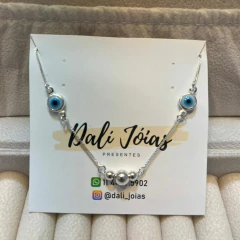 Pulseira em prata 925 com detalhes em olho grego e bolinhas, apresentada em um suporte com logo da Dali Joias.